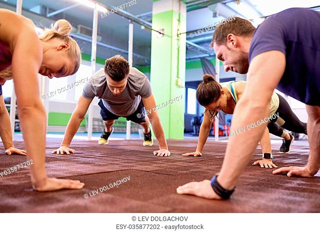 fitness, sport, exercising, training and healthy lifestyle concept - group of people doing straight arm plank in gym