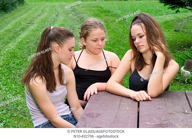 Teen girls and their young sister sitting together at a picnic table