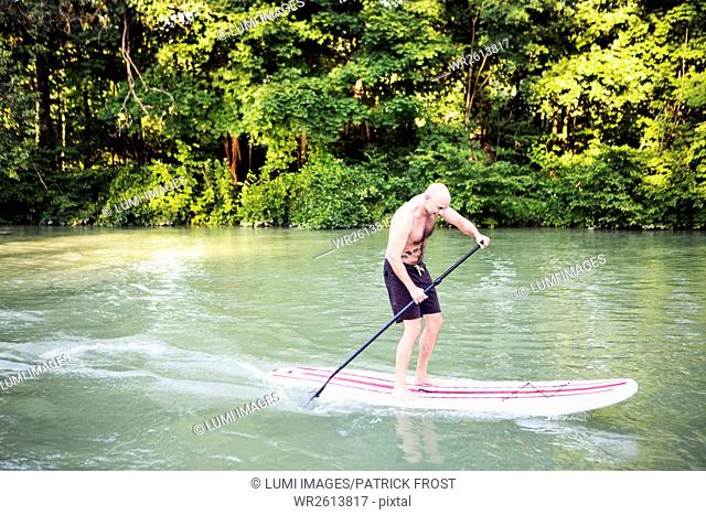 A man is paddling on a stand up paddle boat
