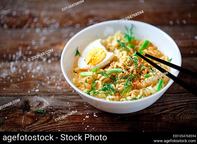 Asian noodles with fresh green onion and boiled egg on old wood table