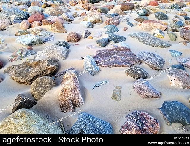 multi-colored stones lie in the sand. View from above