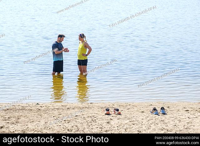 08 April 2020, Lower Saxony, Hanover: Sabrina and Oliver cool off after jogging in the Altwarmbüchener Lake. Photo: Ole Spata/dpa