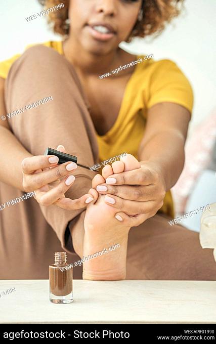 Young woman painting her toenails