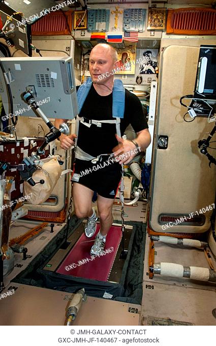 Russian cosmonaut Oleg Artemyev, Expedition 40 flight engineer, equipped with a bungee harness, exercises on the BD-2 Treadmill in the Zvezda Service Module of...