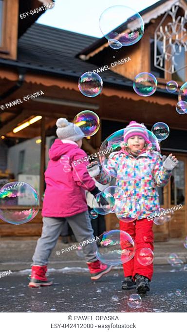 Children trying to catch giant soap bubbles on the main high street in Karpacz town, polish winter ski resort, Poland