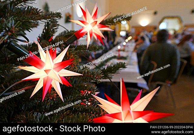 06 December 2023, Thuringia, Erfurt: Advent stars light up the Christmas tree in the Restaurant des Herzens of the Evangelical City Mission. From St