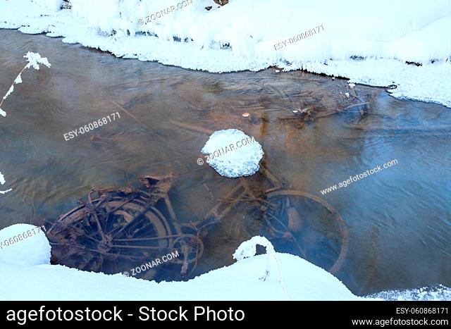 Abandoned bicycle in small stream at winter forest