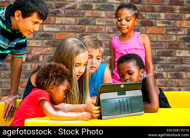 Multiracial group of children looking at tablet outdoors
