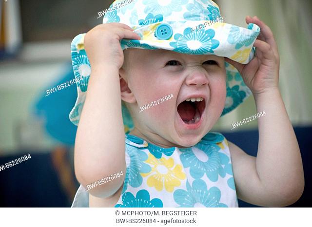 baby in summer cloth holding her sunhead tight screaming jauntily