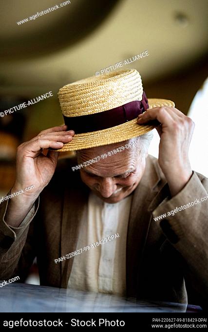 PRODUCTION - 22 June 2022, Berlin: Ulrich Tukur, actor, musician and writer, puts on a hat during a portrait appointment at the Komödie am Kurfürstendamm in the...