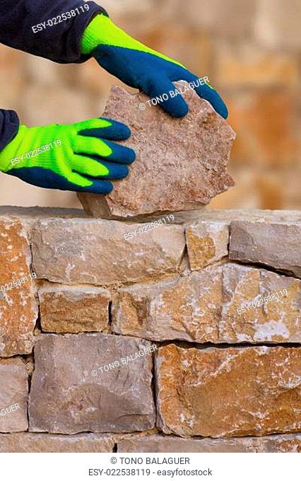 Mason hands working on masonry stone wall
