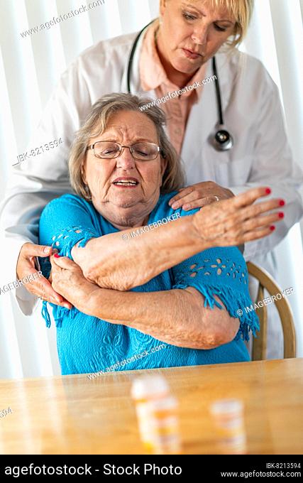 Female doctor helping senior adult woman with arm exercises