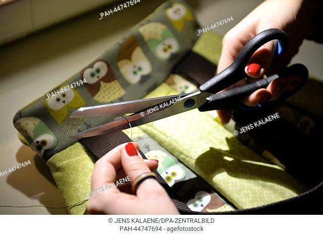 A young woman sews in her apartment in Berlin, Germany, 13 November 2013. More and more women start to sew at the moment