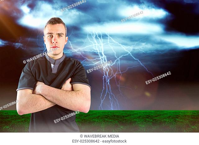 Composite image of frowning rugby player with arms crossed