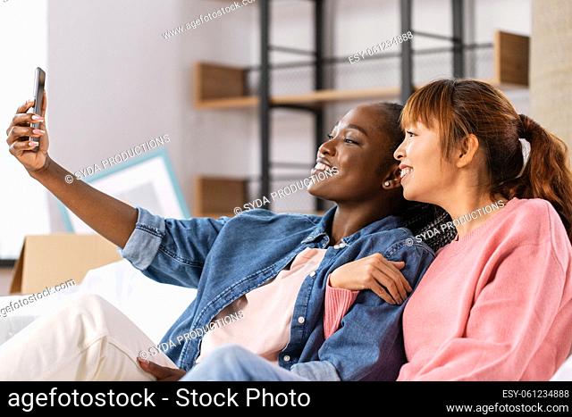 women with smartphone taking selfie at new home