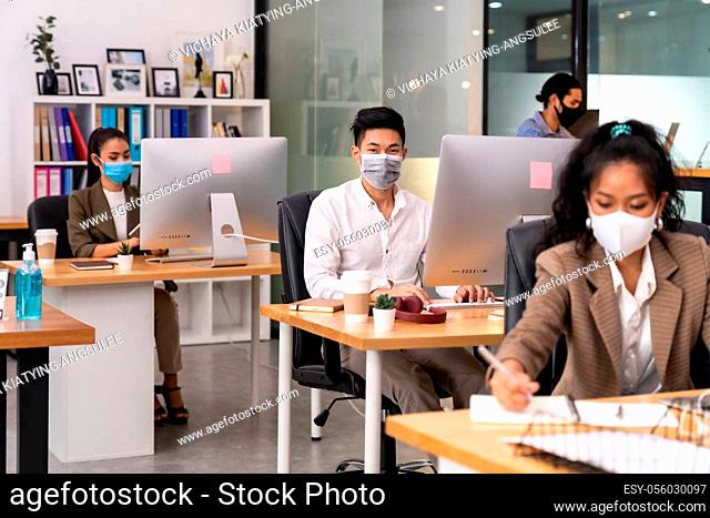 Mixed race of African black and asian business woman wear face mask working in new normal office with social distance to Group of business team people to...