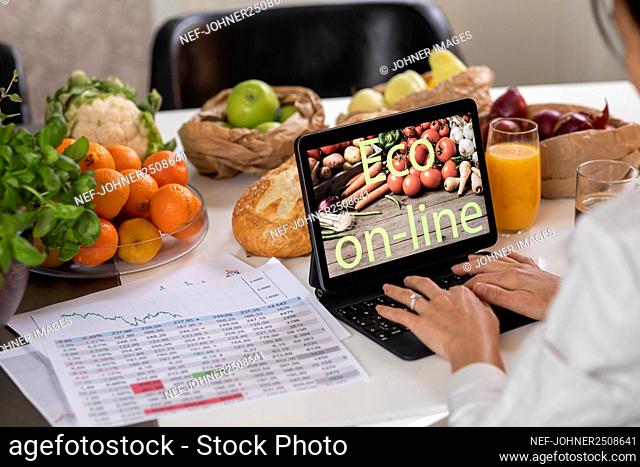 Woman's hands using laptop in kitchen
