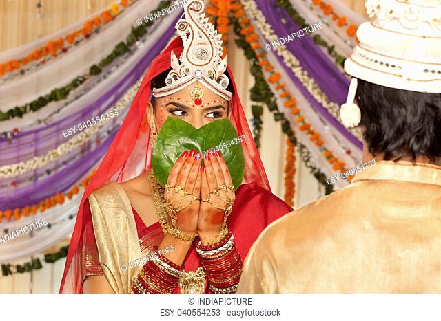 Bengali bride hiding her face from the groom