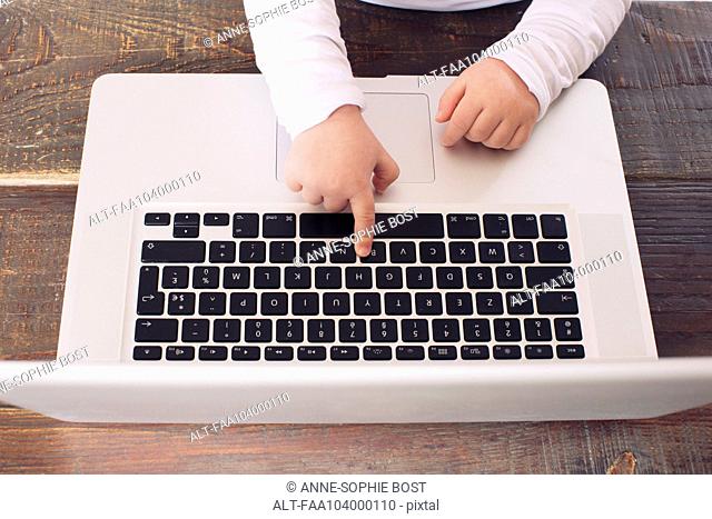 Child using laptop computer, cropped