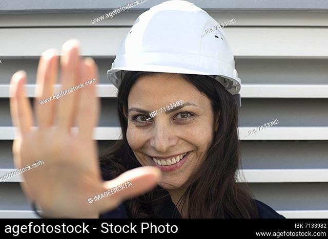 Middle-aged woman with dark hair and helmet in front of a power plant, Freiburg, Baden-Württemberg, Germany, Europe