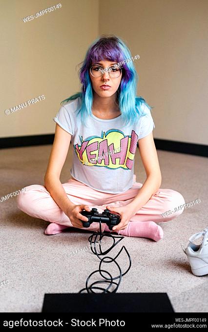Trendy blue haired woman playing video game at home