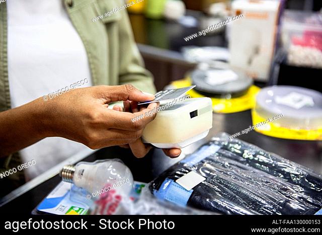 African American hardware shop worker processing credit card payment