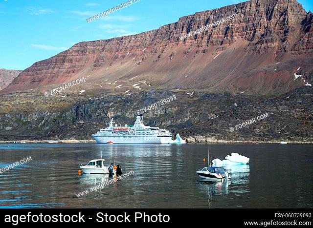 Ilulissat, Greenland - July 06, 2018: A big cruise ship and fishing boats anchored in Qeqertarsuaq harbor