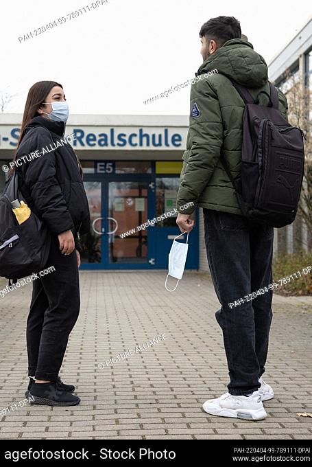 04 April 2022, North Rhine-Westphalia, Gütersloh: Ashwaq (l) with mask and Abdulrahman stand in a posed situation in front of their secondary school