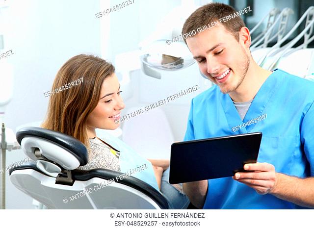 Happy dentist and patient commenting treatments in a tablet application in a consultation with medical equipment in the background