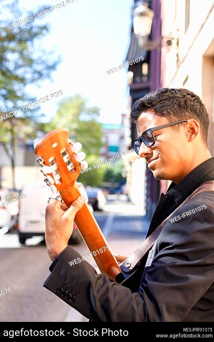 Young male musician playing guitar on street