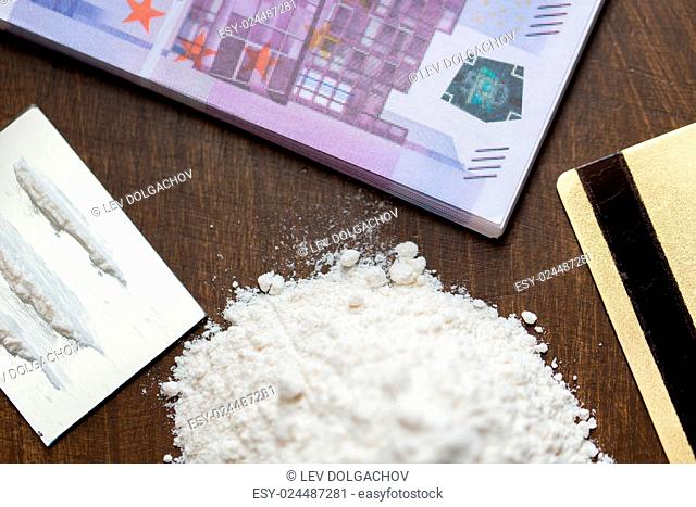 drug use, crime, addiction and substance abuse concept - close up of crack cocaine drug dose track on mirror with credit card and money