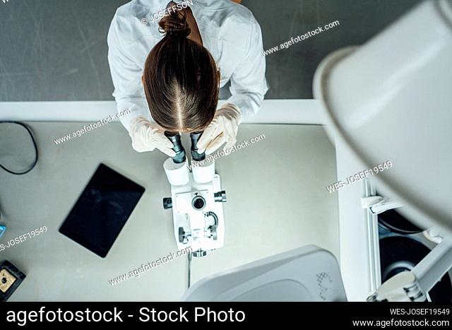Young scientist working with microscope in laboratory