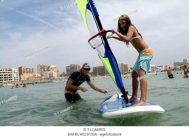 young man giving surf lessons to small girl, Spain, Balearen, Majorca