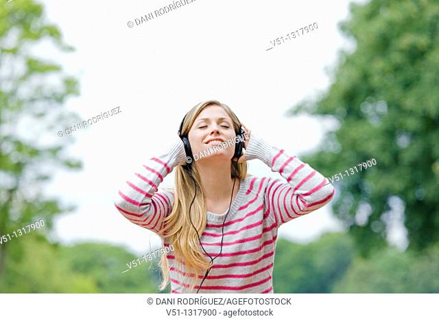 Portrait of a woman with closed eyes listening to music in the park