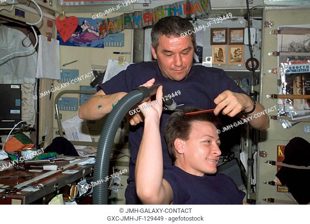 Cosmonaut Valery G. Korzun, Expedition Five mission commander, cuts astronaut Peggy A. Whitson's hair in the Zvezda Service Module on the International Space...