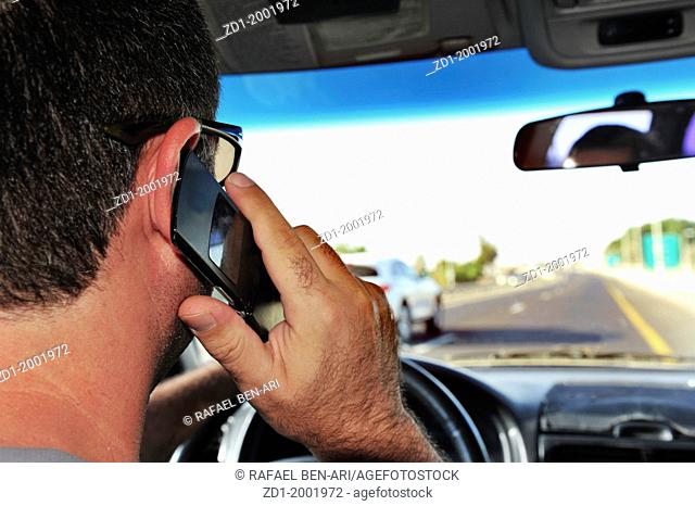 Concept photo of a male driver speaks on a mobile phone while driving