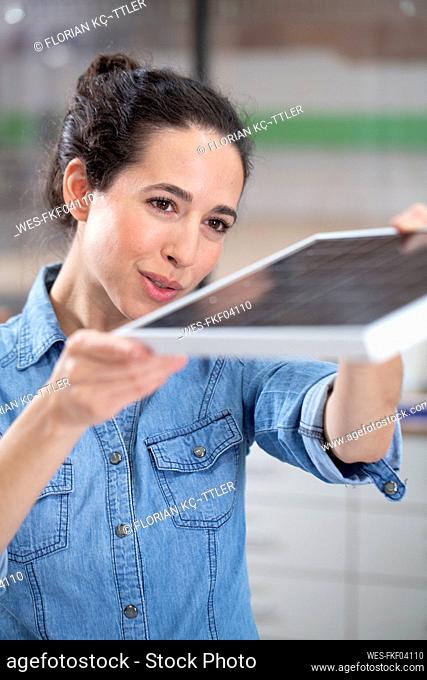 Businesswoman holding solar panel model at office