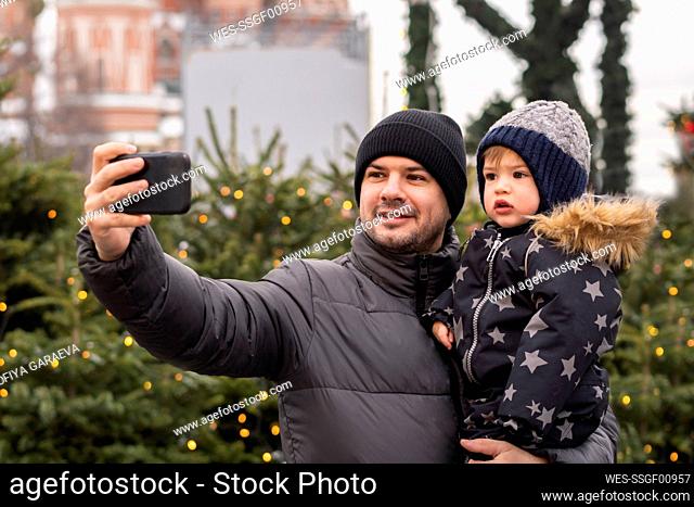 Father taking selfie with son on smart phone in Christmas market