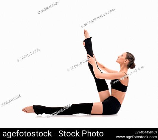 Slim girl in black sportswear streching gracefully isolated profile shot on white background