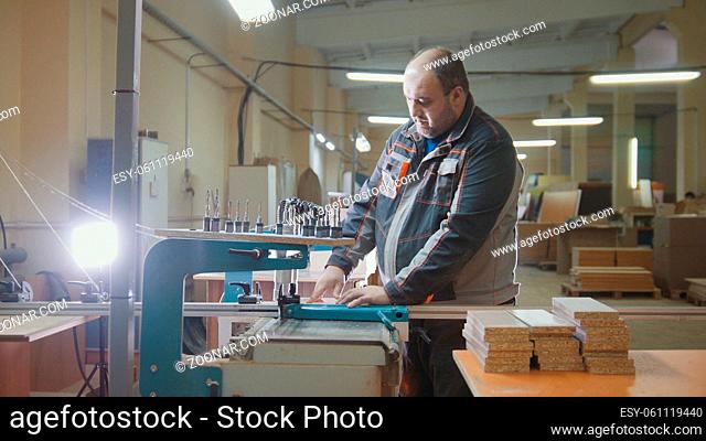 Worker carpenter cut a wooden fragment on a furniture factory, woodworking