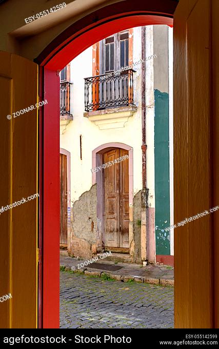 Old door in colonial architecture deteriorated by time seen through another door also old and with the same architecture in the city of Ouro Preto