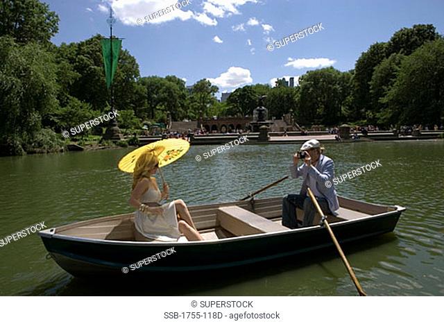 Young man taking a picture of a young woman sitting in a boat, Central Park, Manhattan, New York City, New York, USA