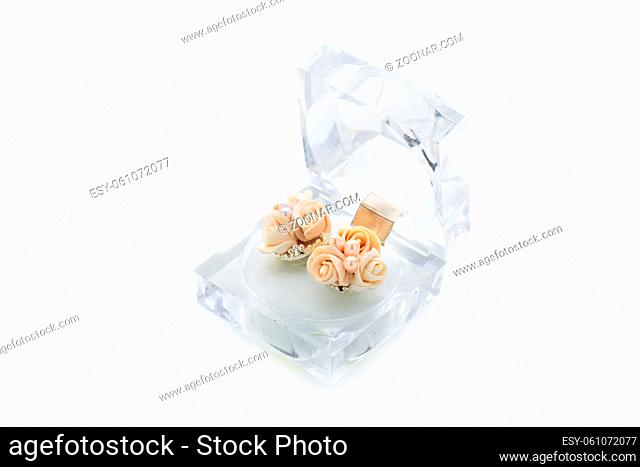 Close-up shot of handmade earrings with flowers inside crystal box. Isolated over white background