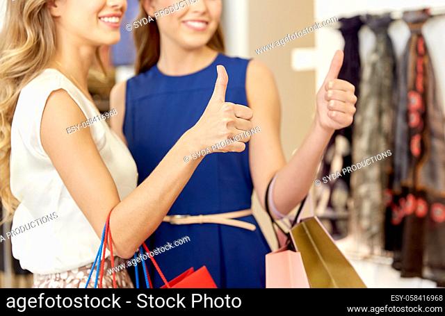happy women with shopping bags showing thumbs up