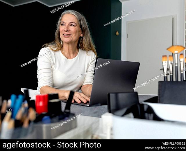 Thoughtful businesswoman sitting with laptop at office