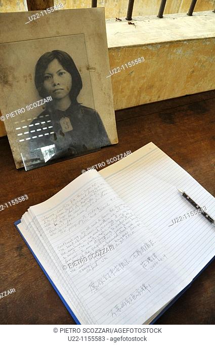 Phnom Penh (Cambodia): a photo of a victim of the Khmer Rouge regime at the Killing Fields of Choeung Ek, by a book with the comments and signatures of visitors