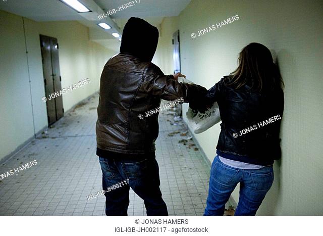 This picture shows a man following a woman in a covered passage as he tries to rape or steal the bag