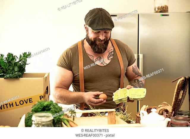 Mature man with delivery service checking eggs, before packing them in cardboard boxes