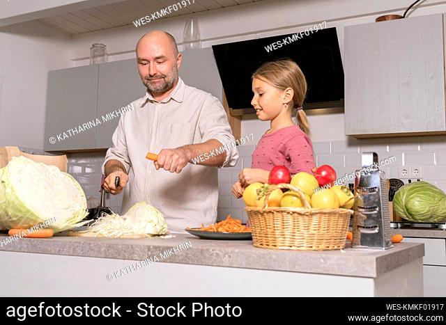 Father and daughter preparing healthy meal in kitchen at home