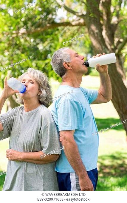 Mature couple drinking water at park